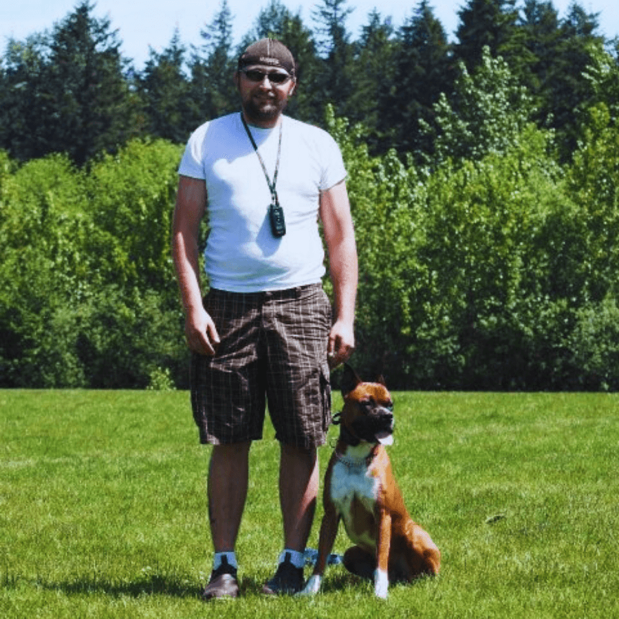 A man standing next to his dog, illustrating common dog behavior problems and training solutions.